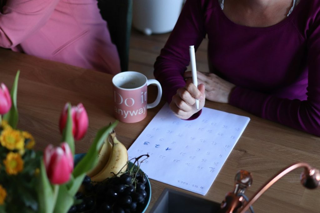 Person writing a weekly plan in a notebook